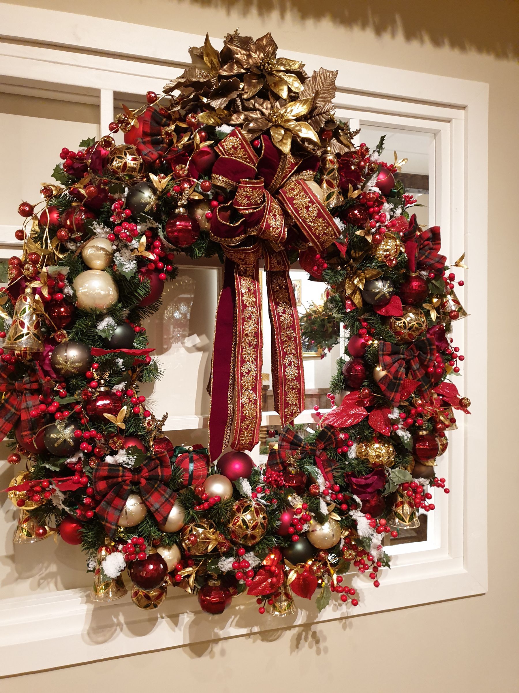 A large christmas wreath is hanging on a window.