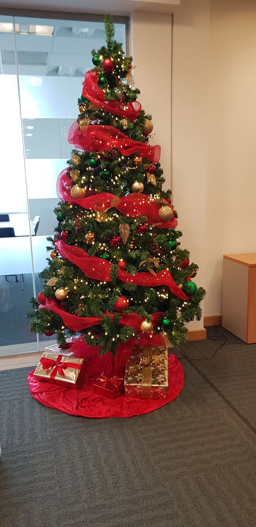A christmas tree decorated in red and gold is sitting in a room.