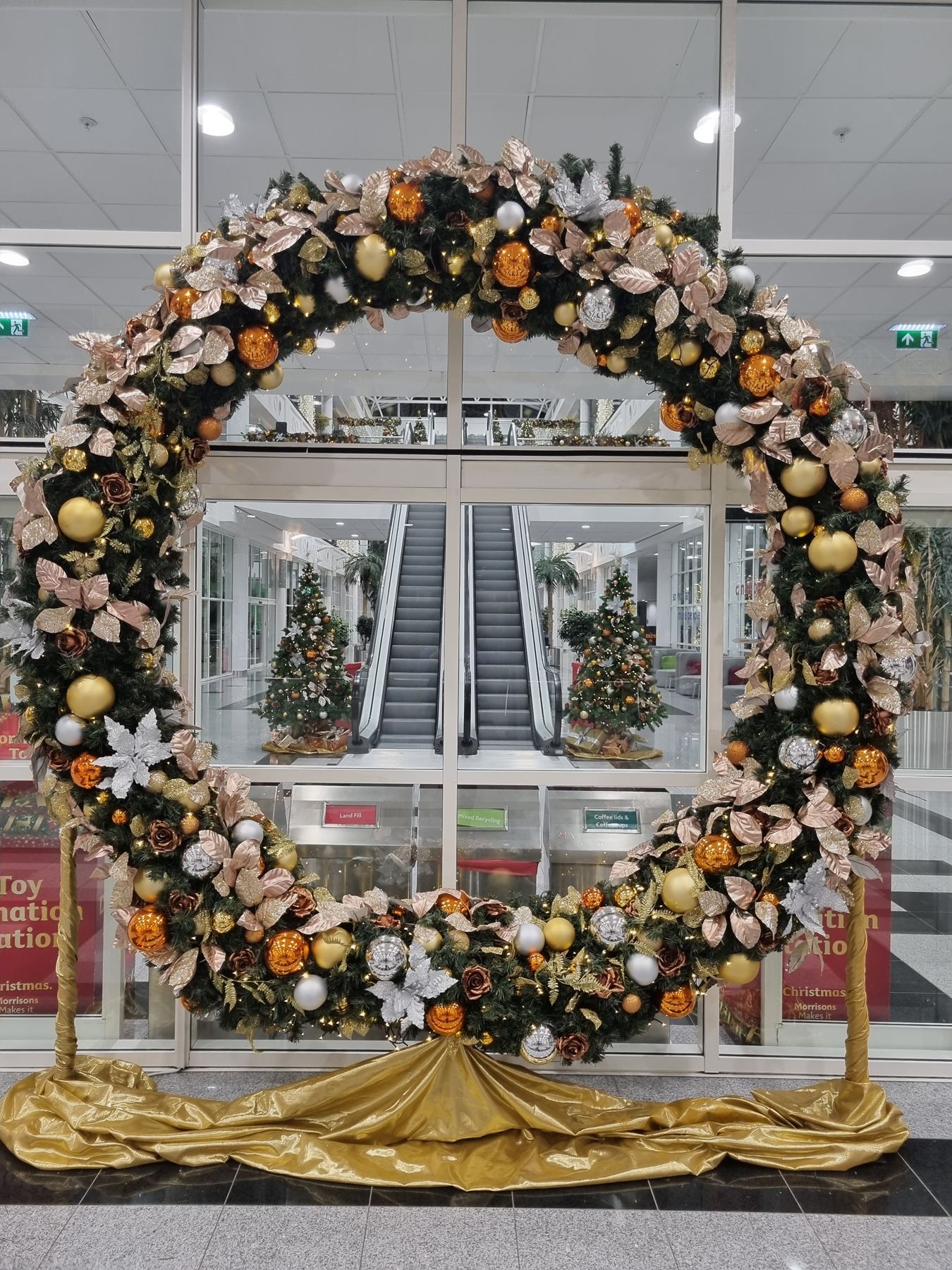 A large christmas wreath is sitting in front of a glass door.