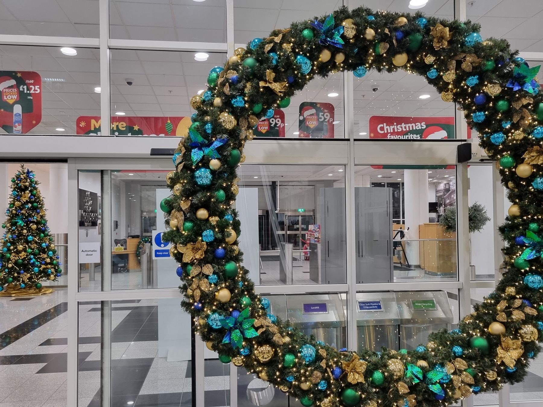 A large christmas wreath is hanging in front of a glass door.