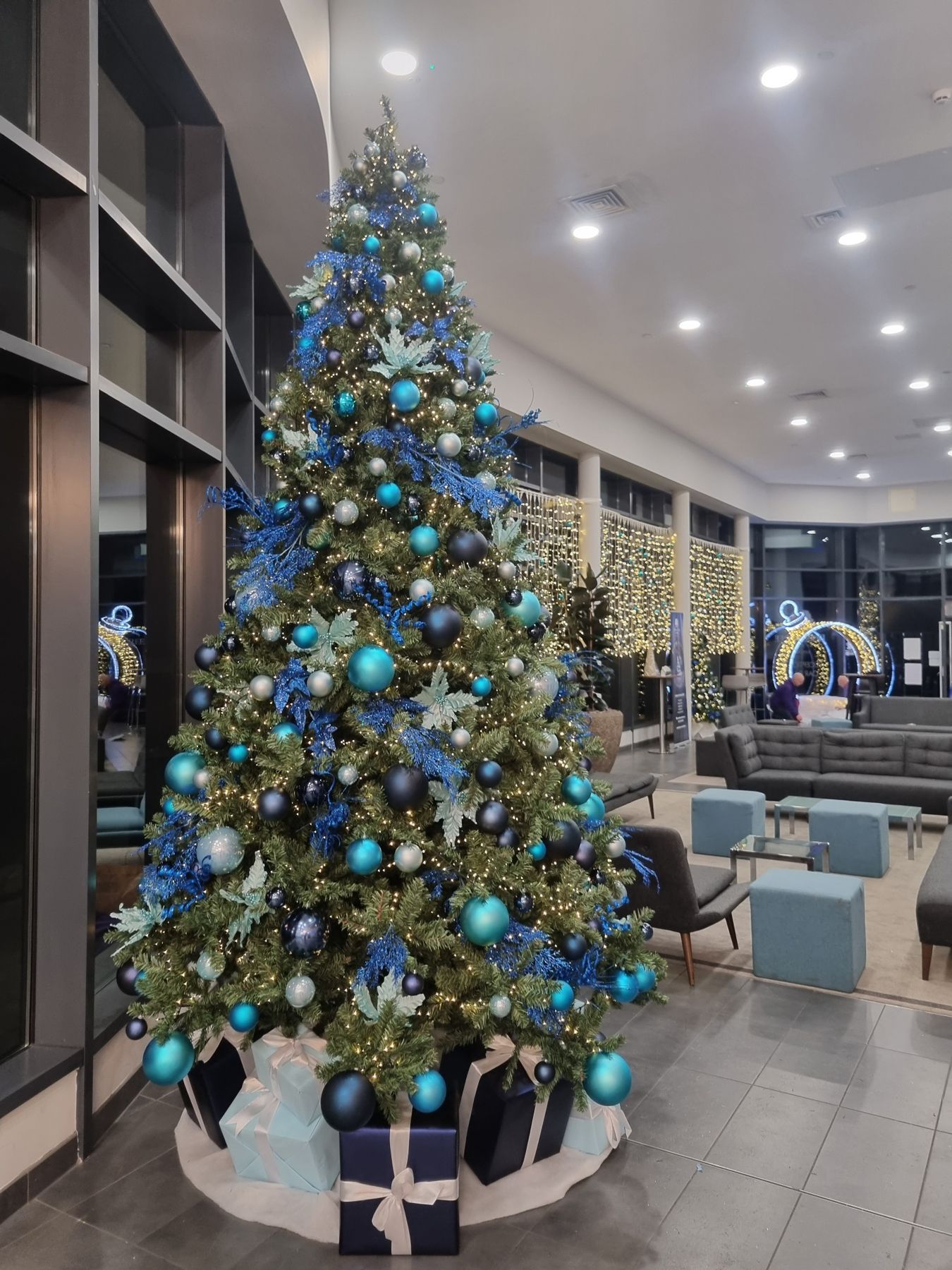 A large christmas tree is sitting in the middle of a living room.