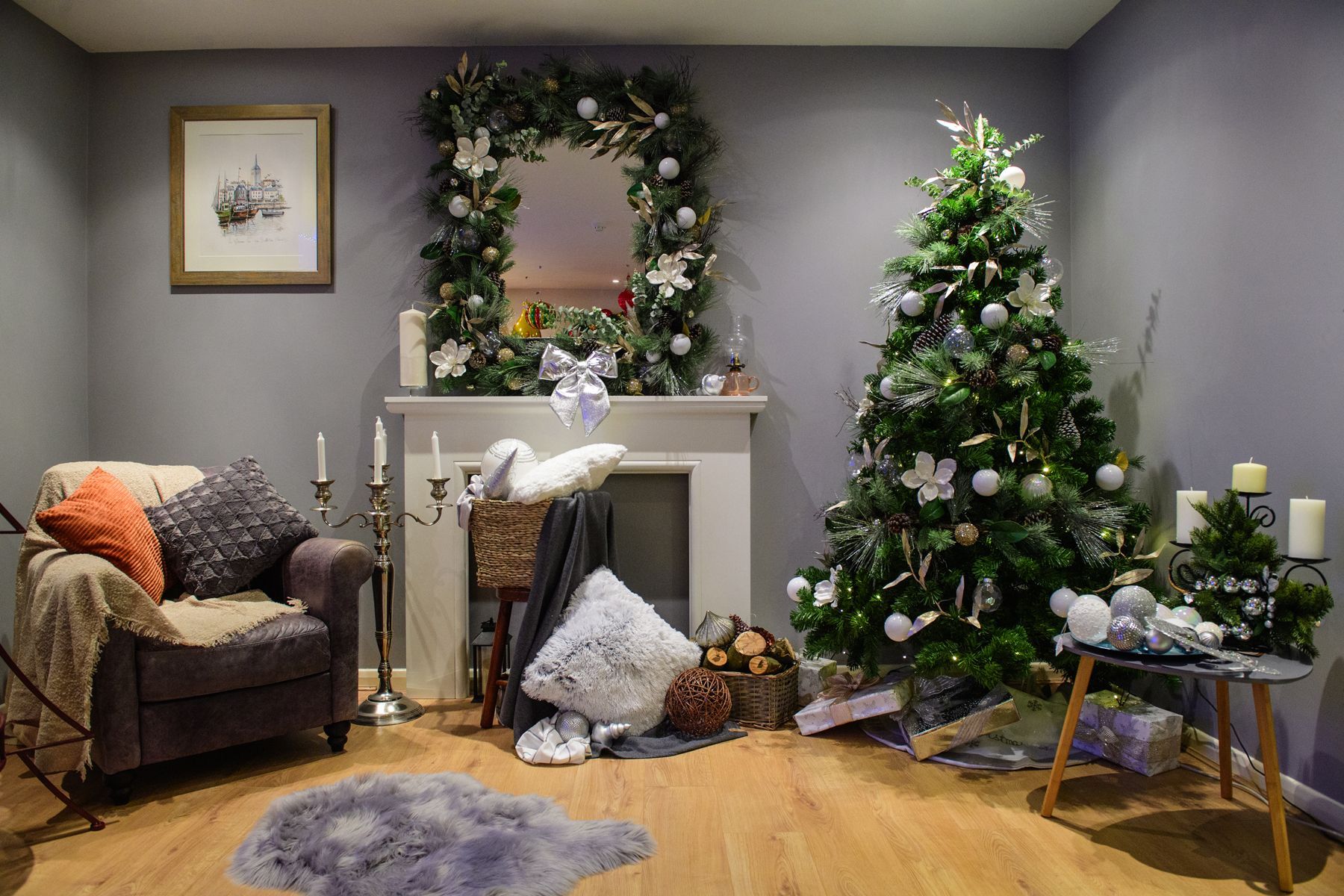 Cozy living room with Christmas decor, tree, garland, fireplace mantel, and wrapped gifts under warm lights