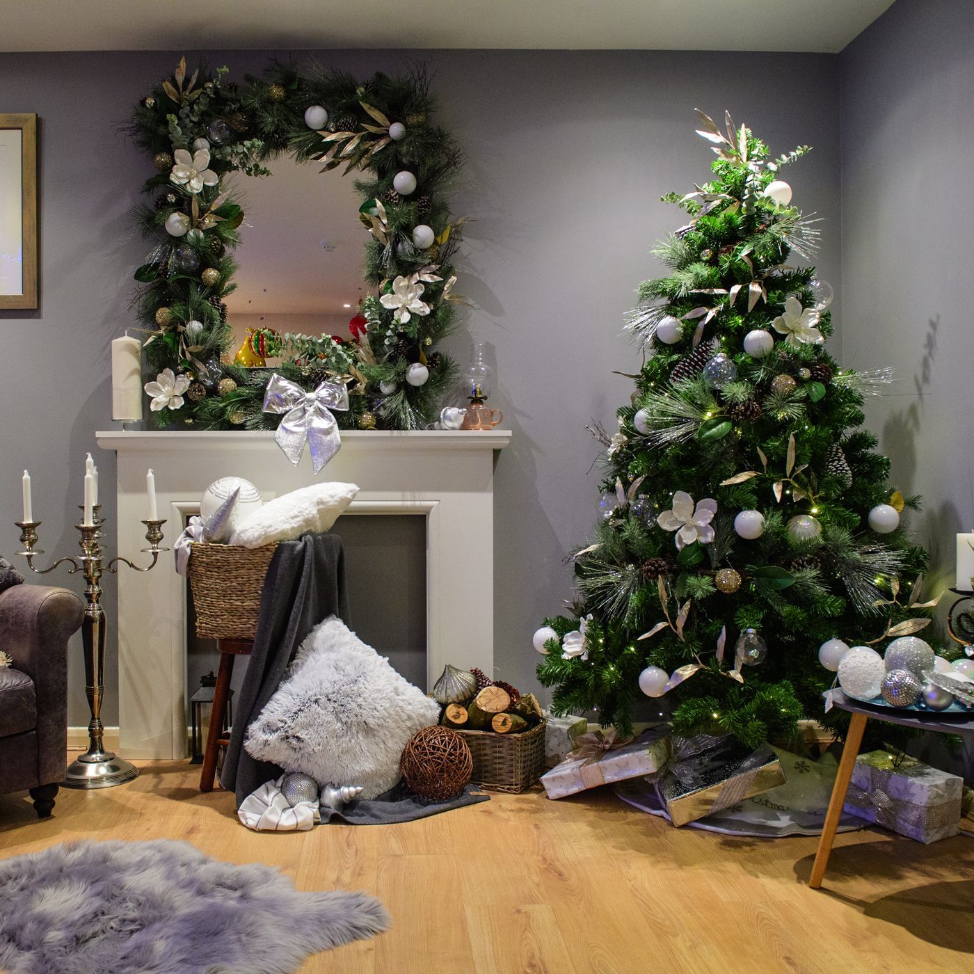 A living room with two christmas trees and a fireplace.