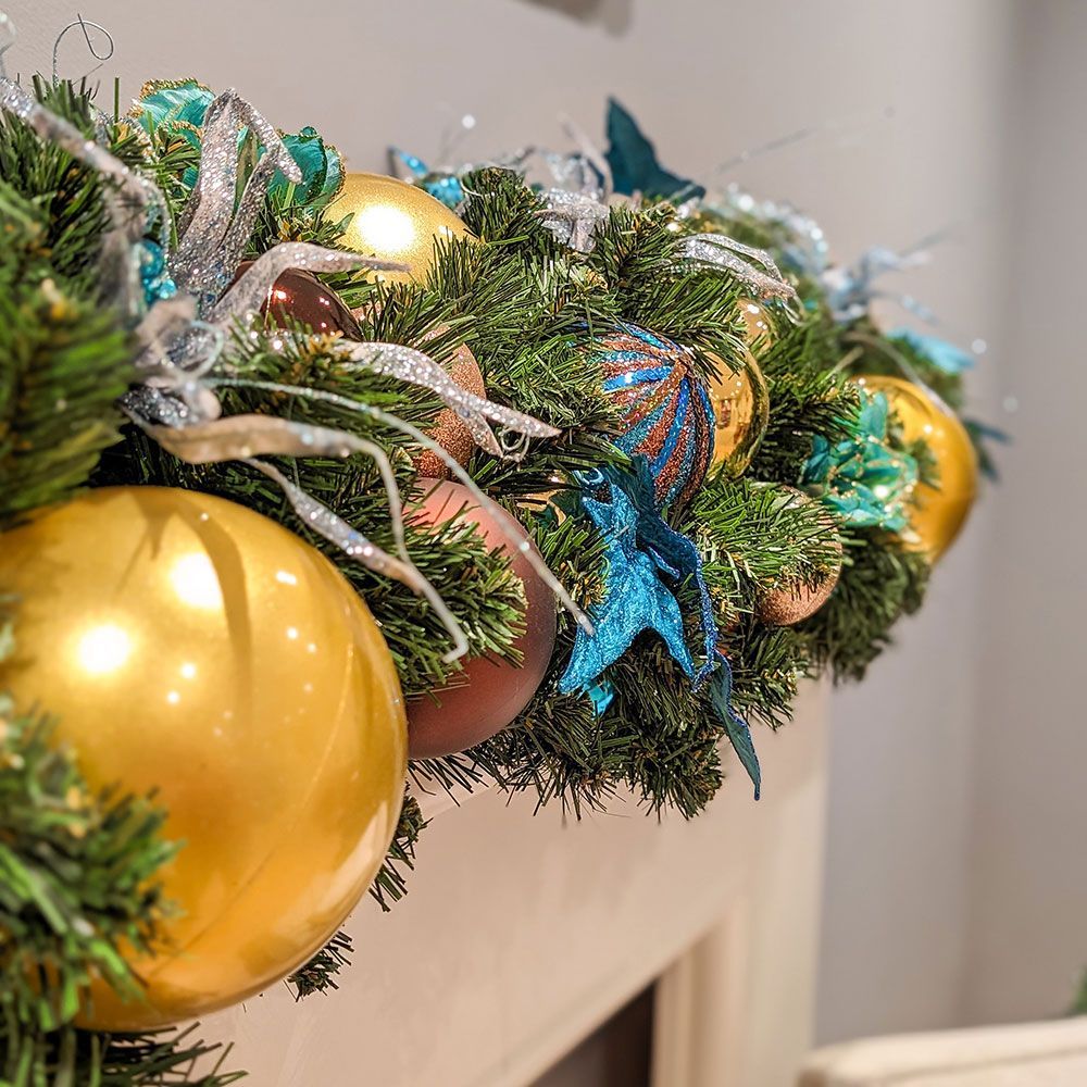 A christmas mantle decorated with gold and blue balls and starfish.