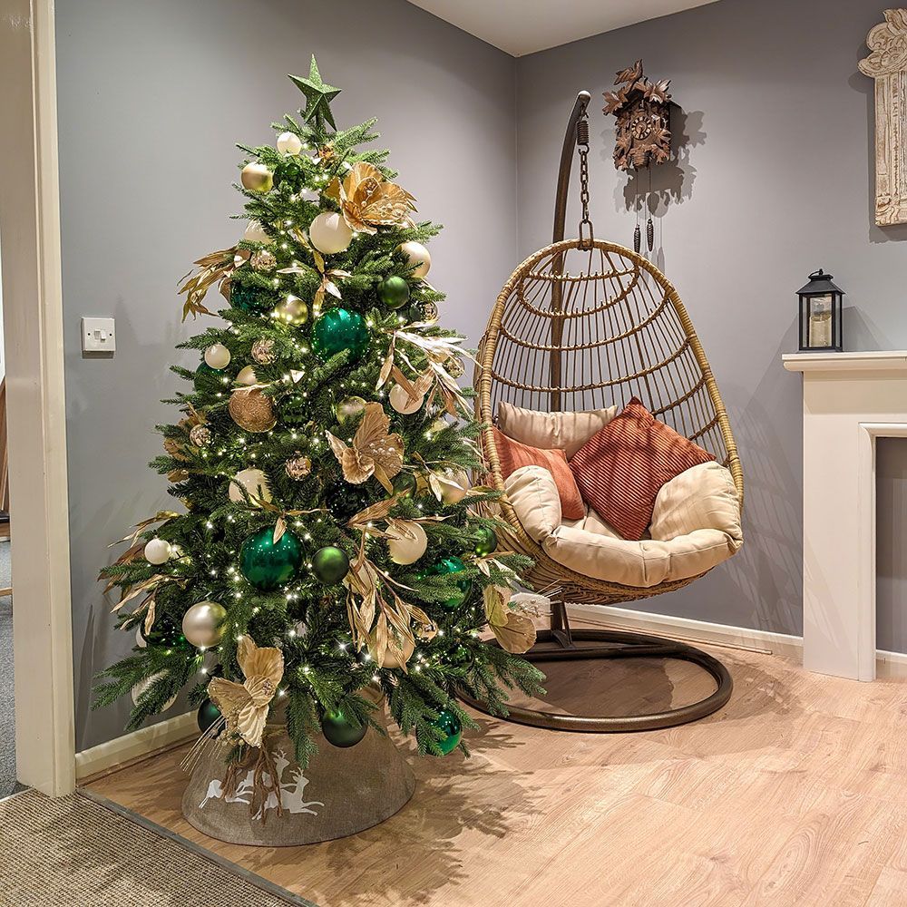 A christmas tree is sitting next to a chair in a living room.