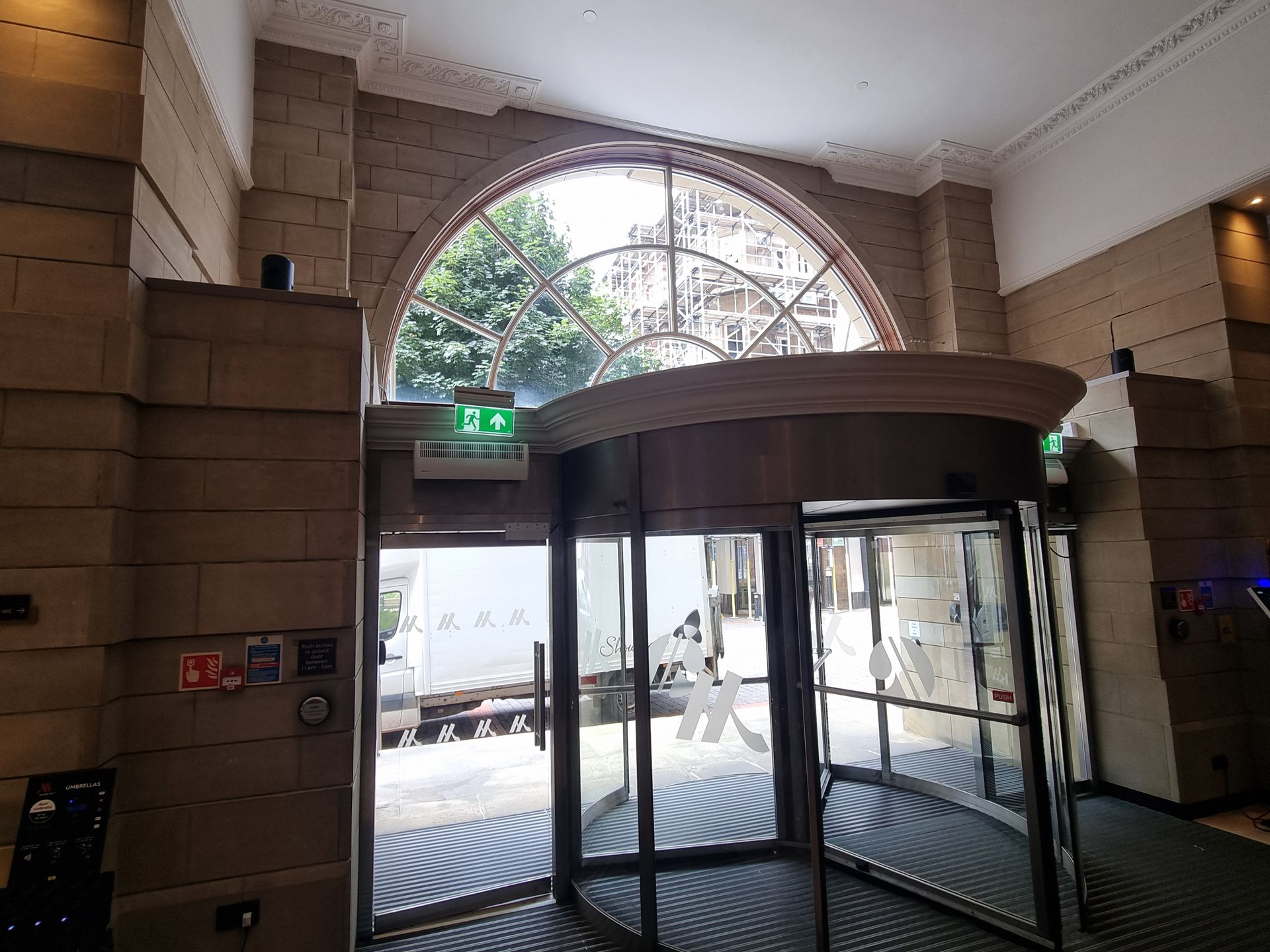 Glass revolving door in a stone entryway with daylight streaming in from outside.