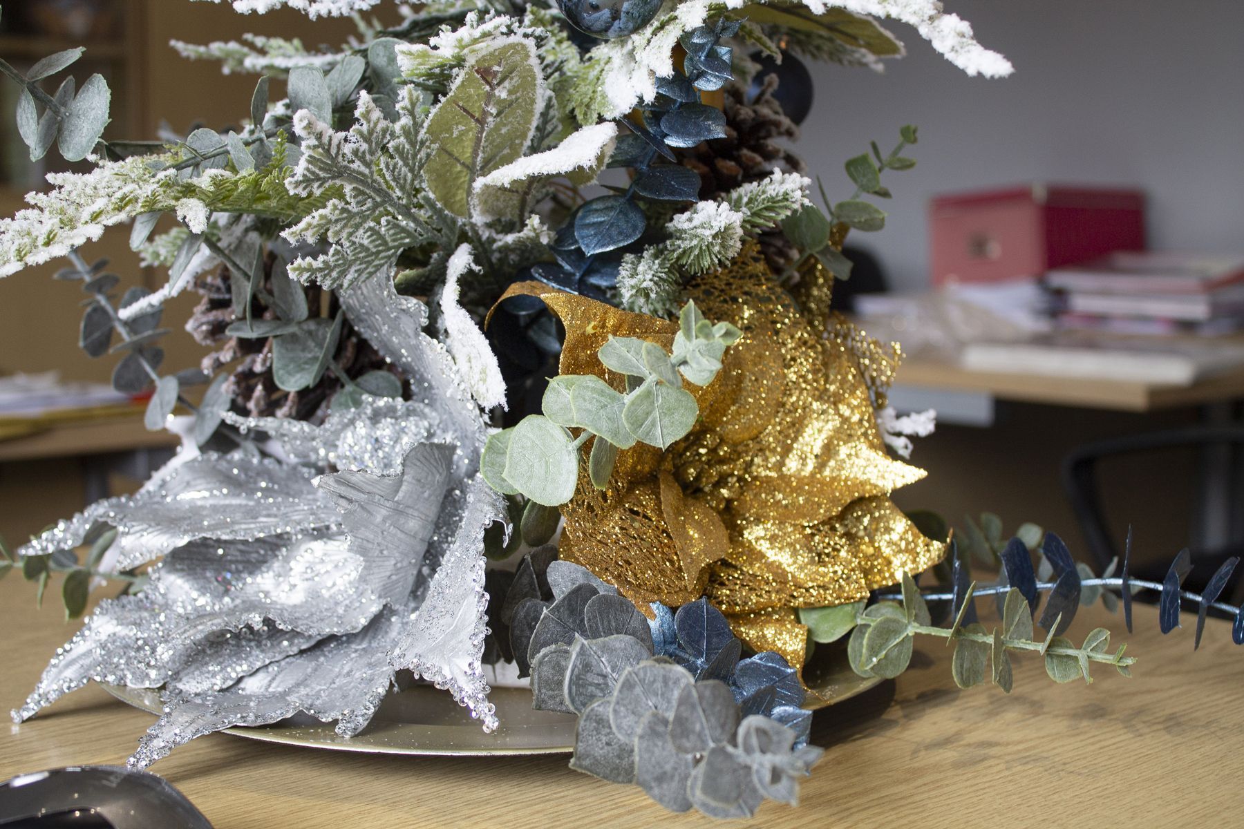 A vase filled with flowers and leaves is sitting on a table.