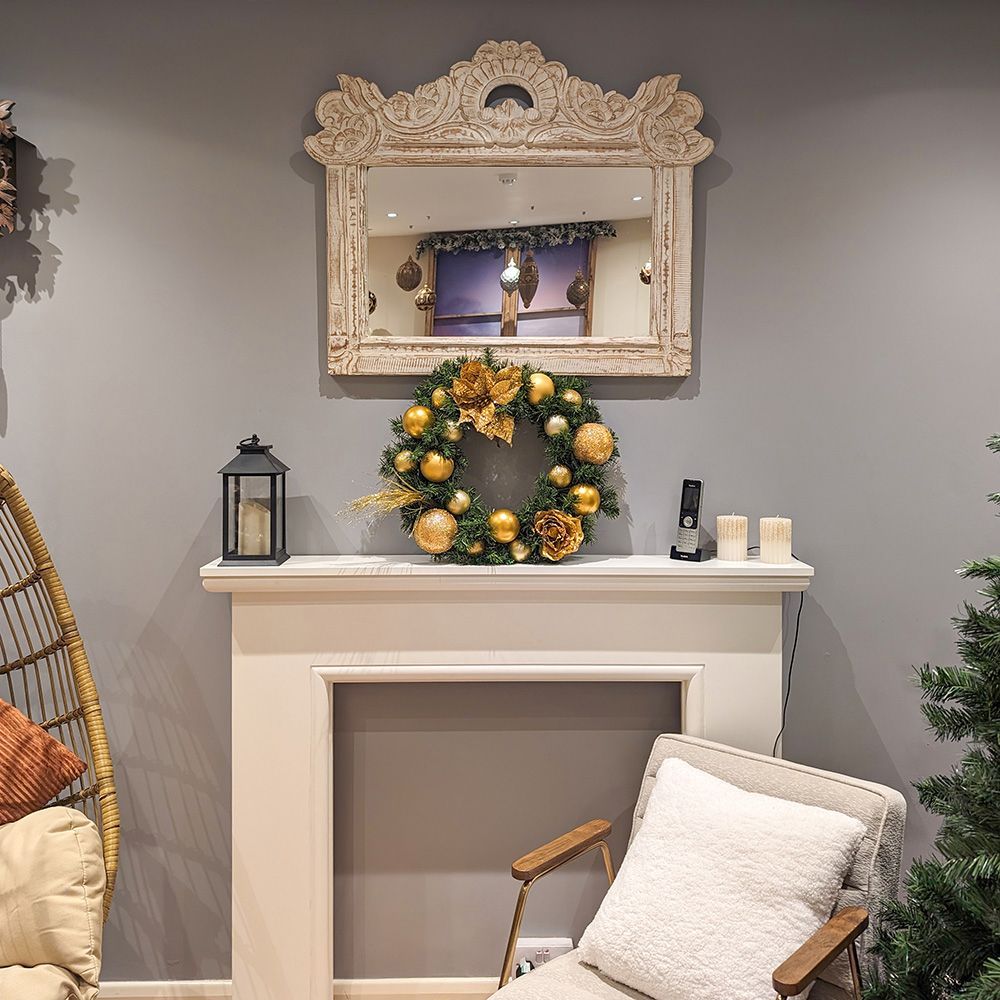 A fireplace with a wreath on top of it and a mirror above it.