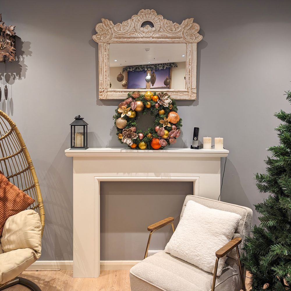 A living room with a chair a fireplace and a christmas wreath.