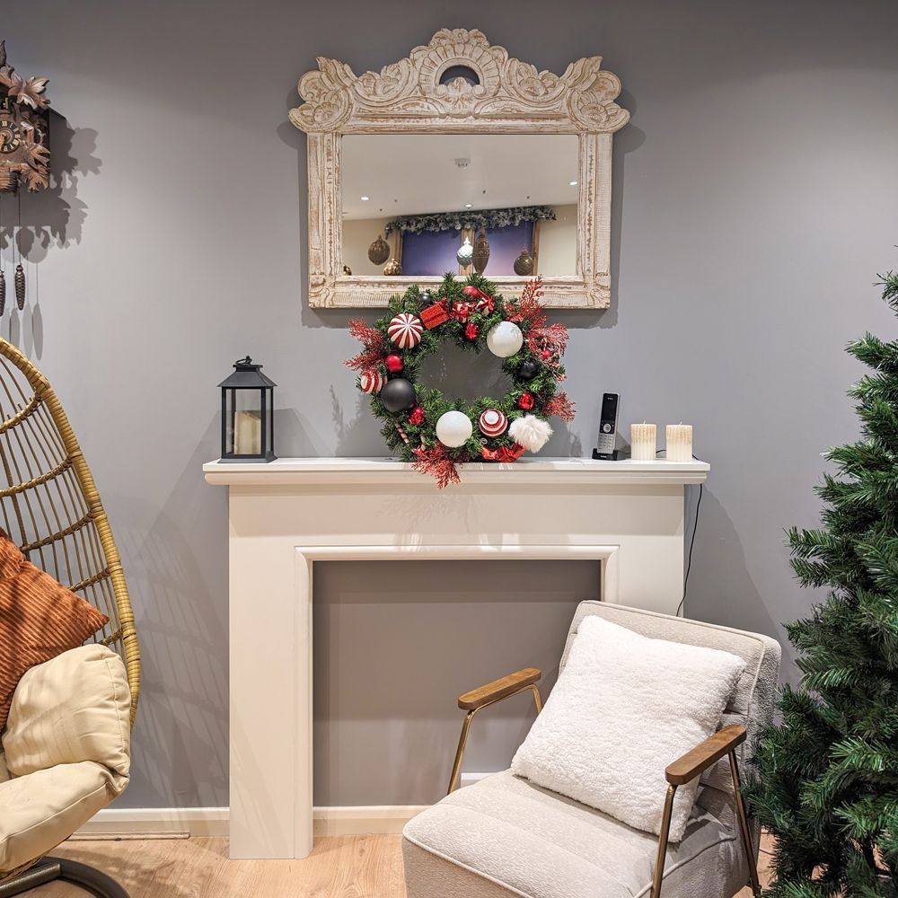 A living room with a chair and a christmas wreath.