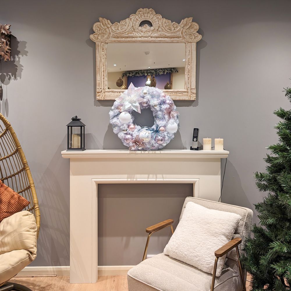 A living room with a chair a fireplace and a christmas wreath.