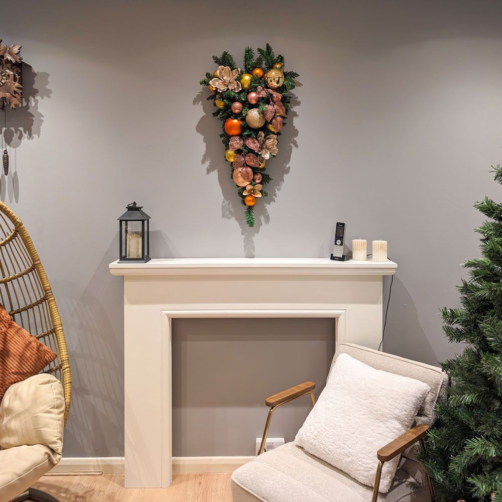 A living room with a chair a fireplace and a christmas wreath.