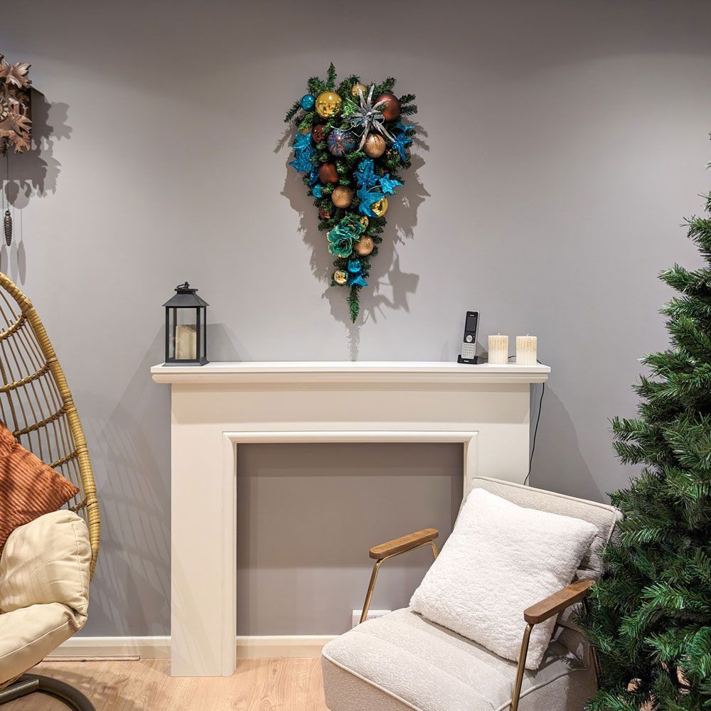 A living room with a chair a fireplace and a christmas wreath.