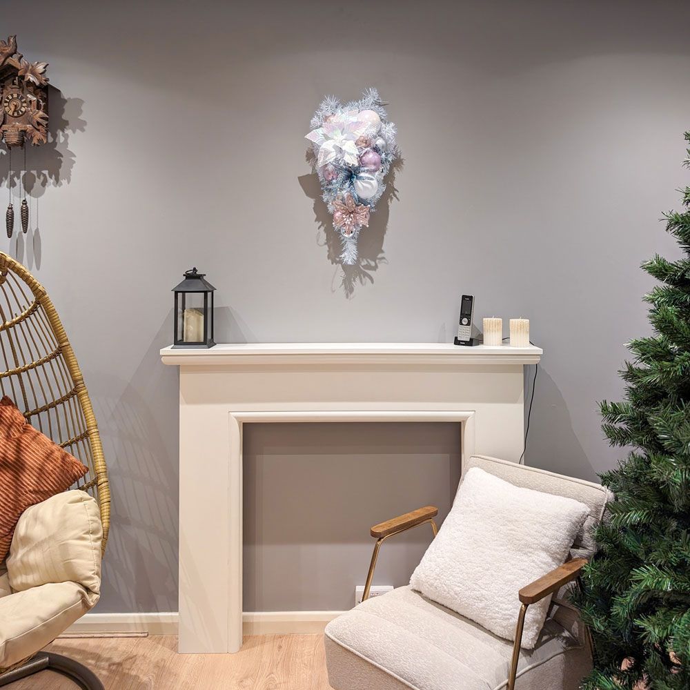 A living room with a fireplace , chair , and christmas wreath.