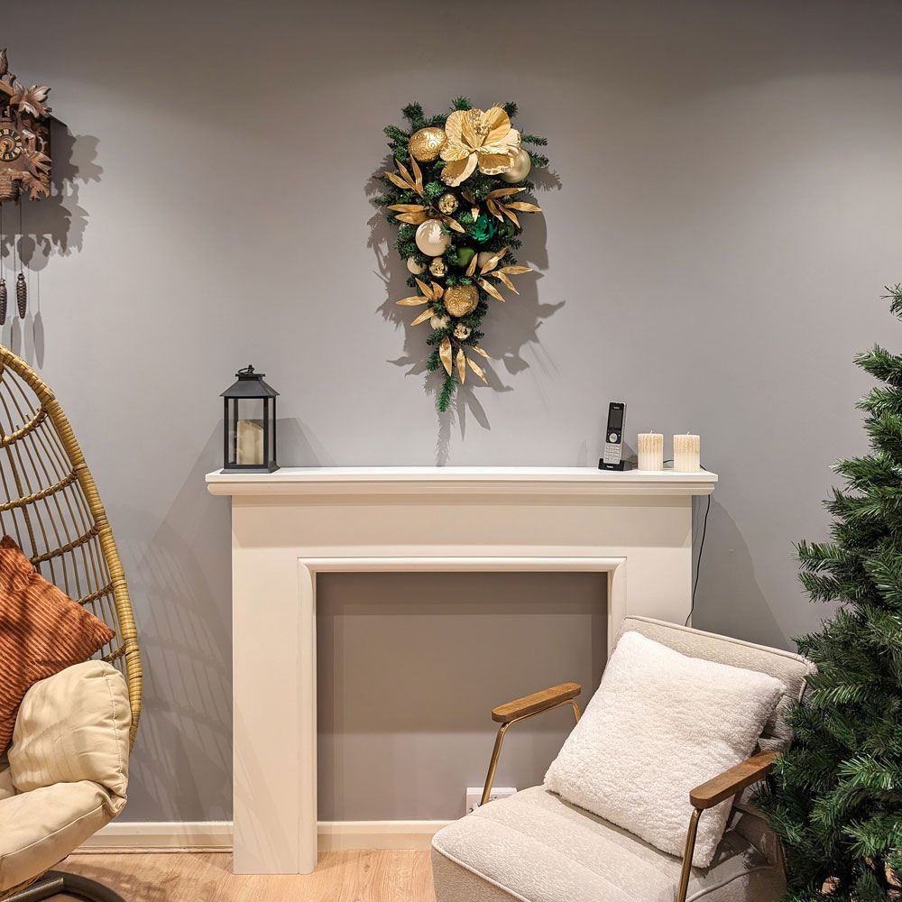 A living room with a fireplace , chair , and christmas wreath.