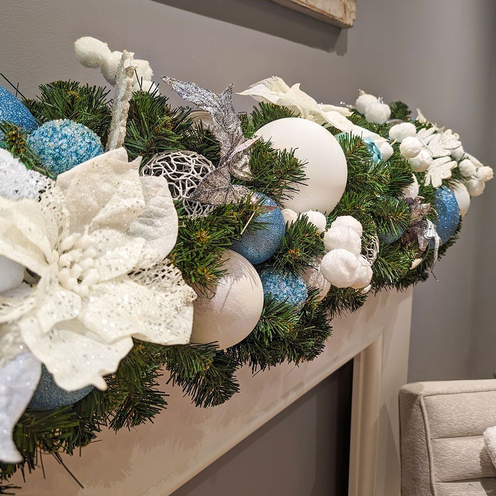 A fireplace mantle decorated for christmas with blue and white decorations.
