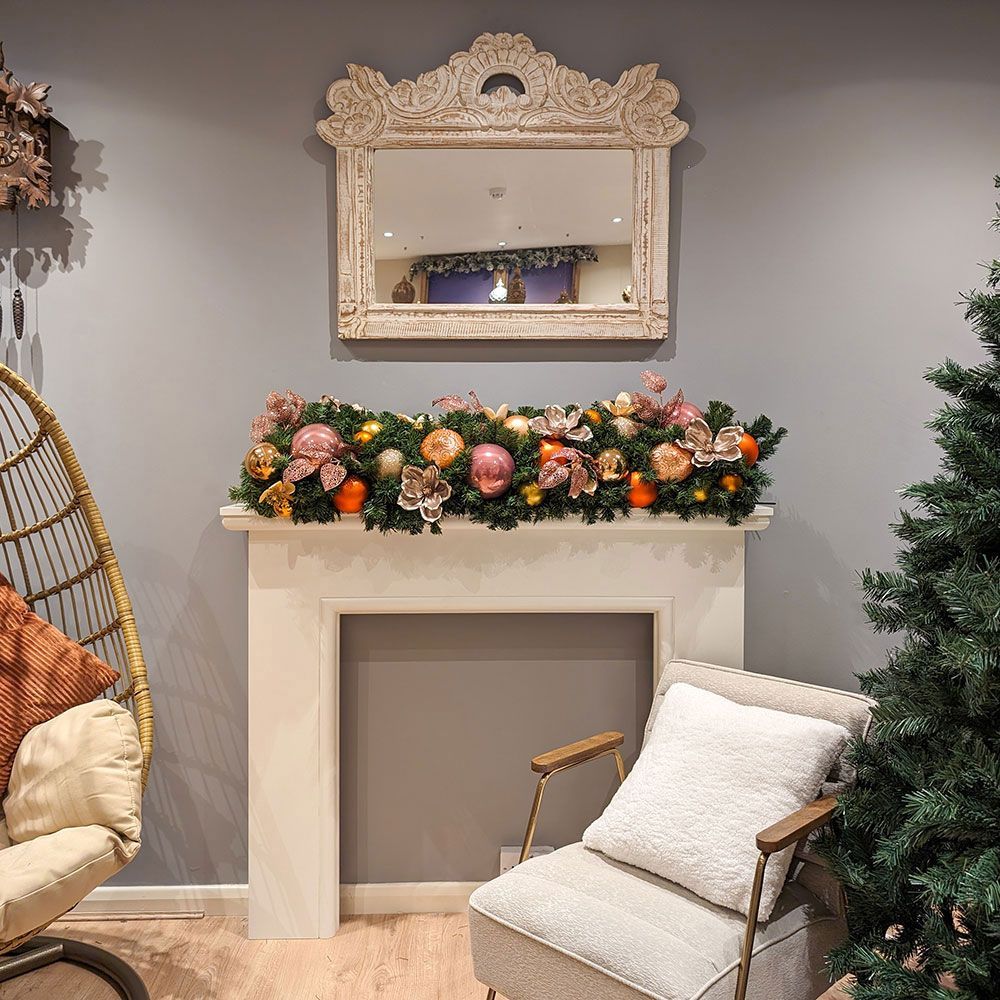 A living room with a chair a fireplace and a christmas garland.