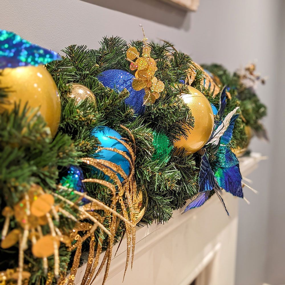 A mantle decorated for christmas with blue and gold decorations.