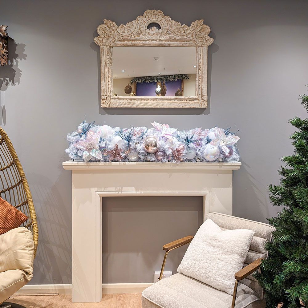A living room with a chair a fireplace and a christmas garland.
