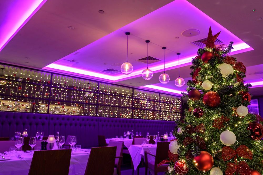 Festively decorated banquet hall with purple lighting and a Christmas tree in the foreground