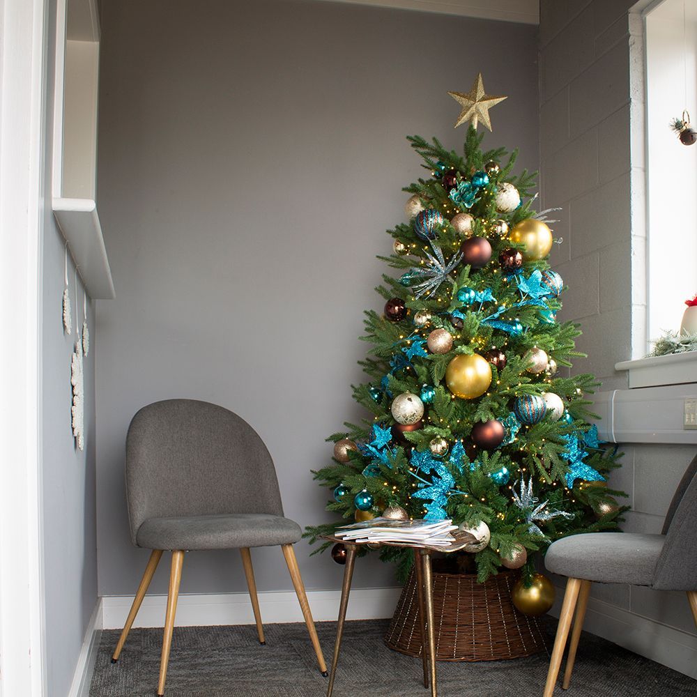 Small decorated Christmas tree in a gray room with two chairs and a window