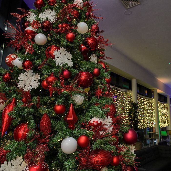 Decorated Christmas tree with red, white, and silver ornaments in an indoor lobby or mall