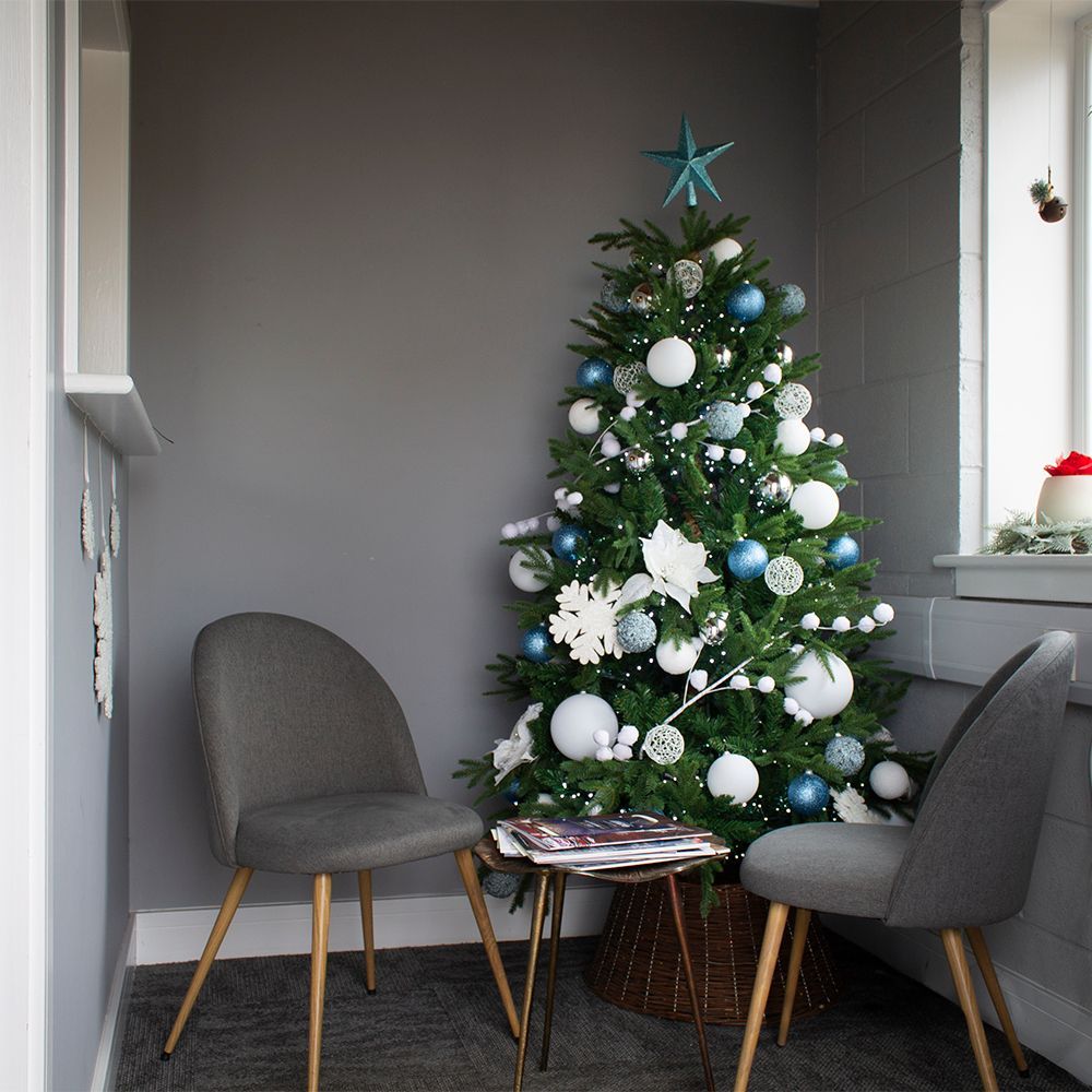 Decorated Christmas tree beside two gray chairs on a small balcony seating area
