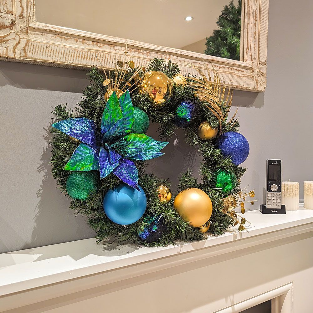 Decorated evergreen garland with blue and gold ornaments draped over a mantel or shelf