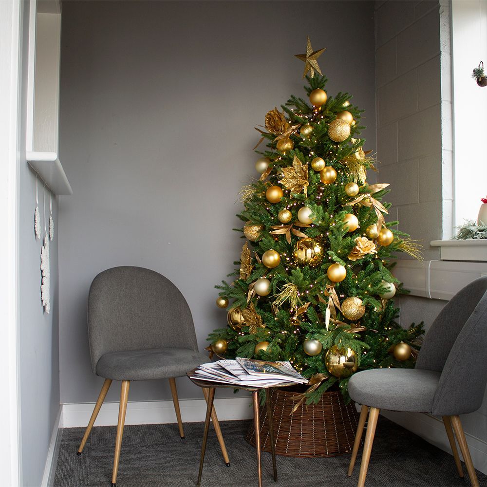 Cozy corner with a decorated Christmas tree, two gray chairs, and a small table in a gray room