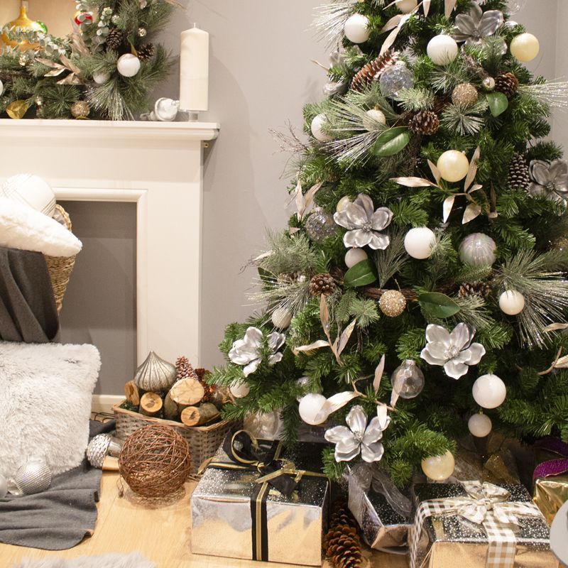 A christmas tree is sitting in a living room next to a fireplace.