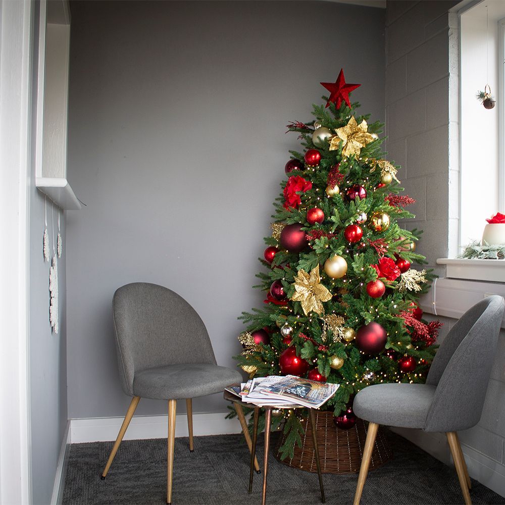 Decorated Christmas tree beside two gray chairs in a small gray room
