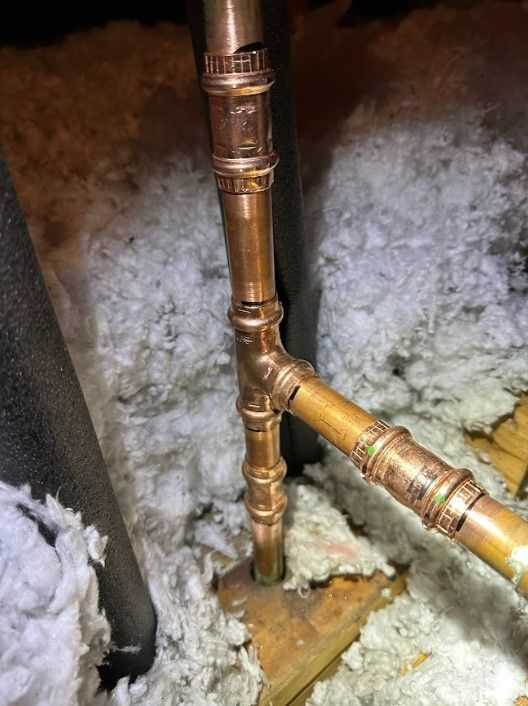 A close up of a copper pipe in an attic.