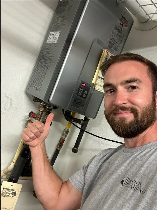 A man with a beard is giving a thumbs up in front of a water heater.