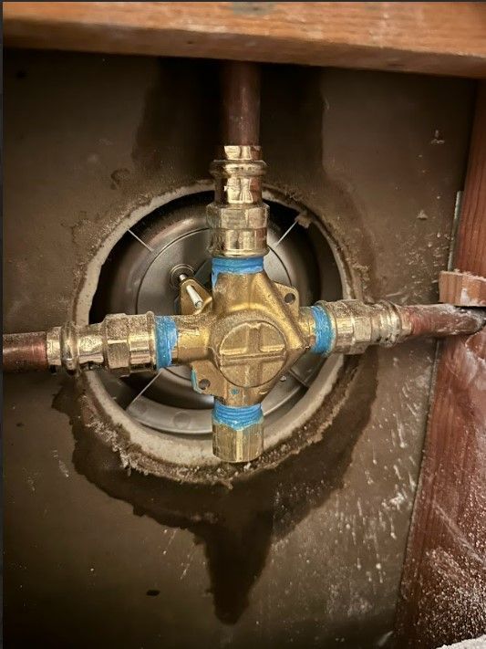 A close up of a brass valve in a hole in a wall.