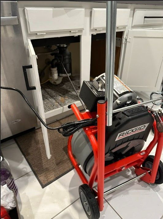 A drain cleaner is sitting under a sink in a kitchen.