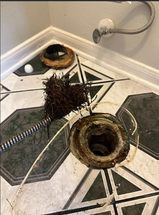 A drain hole in a bathroom with a hose attached to it.