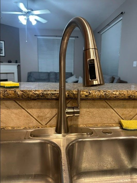 A kitchen sink with a faucet and sponges on the counter.