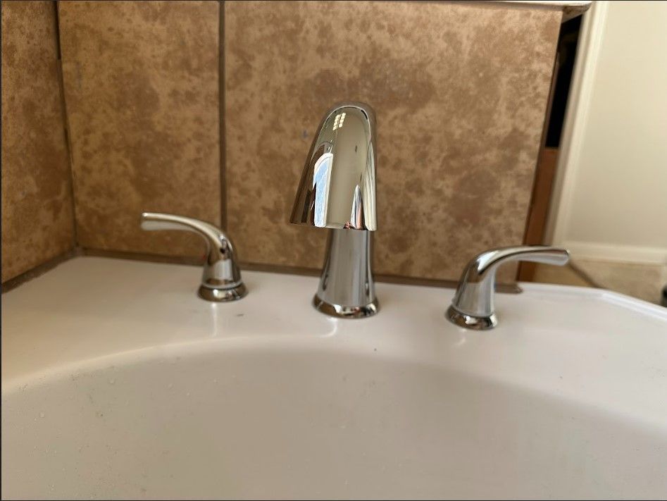 A bathroom sink with a chrome faucet and three handles