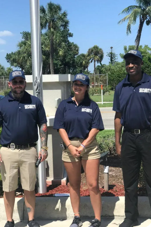 Three uniformed security personnel standing outdoors near a flagpole.