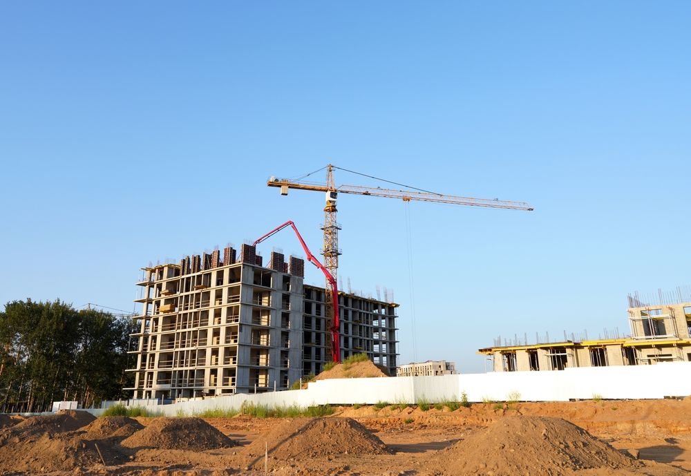 Construction site with crane, unfinished buildings against a clear blue sky.