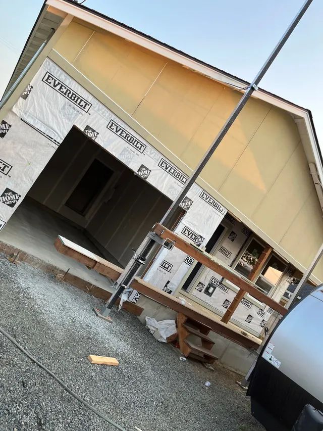 A house that is being built with a car parked in front of it.