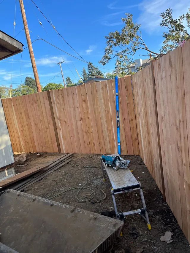 A wooden fence is being built in a backyard.
