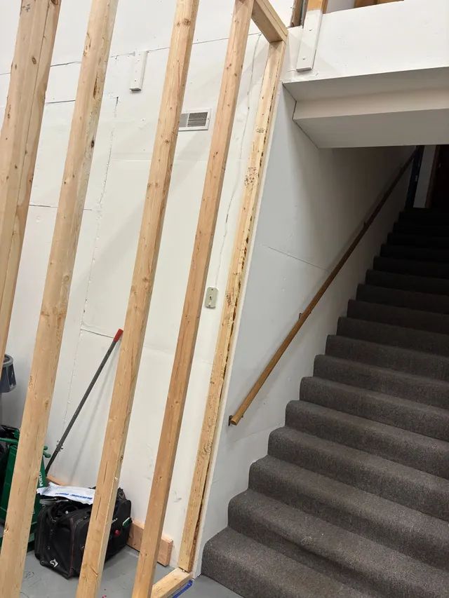 A staircase with a wooden railing is under construction