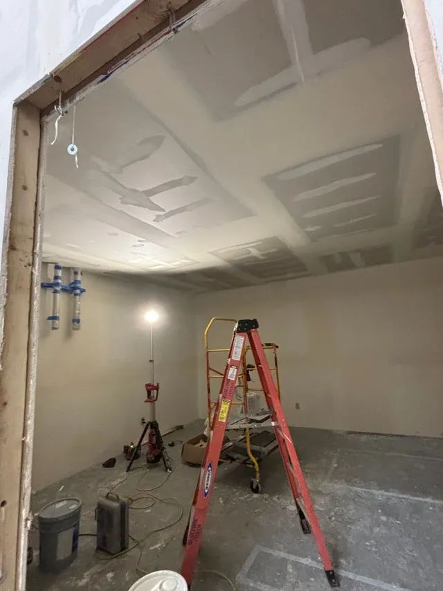 A ladder is sitting in the middle of a room under construction.