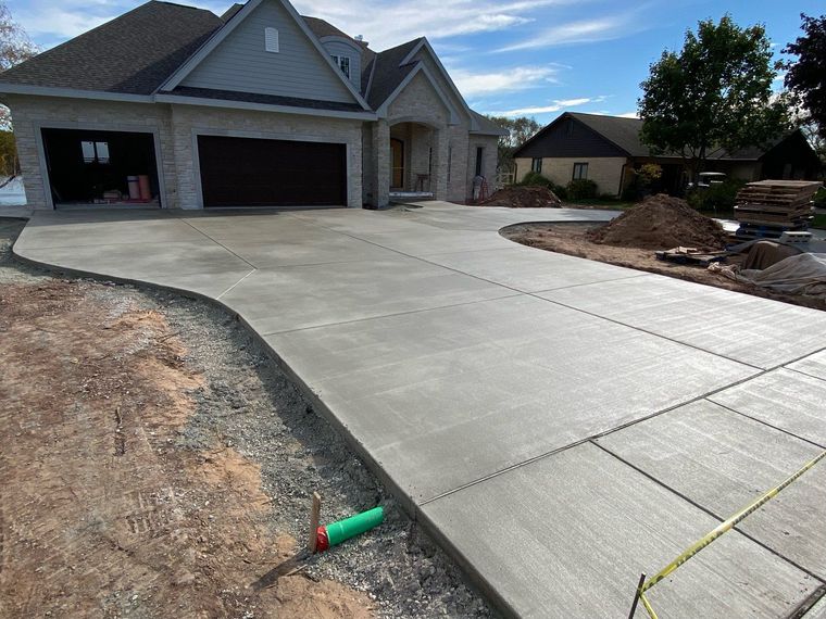 Concrete Services: Newly installed concrete driveway and walkway beside a residential home