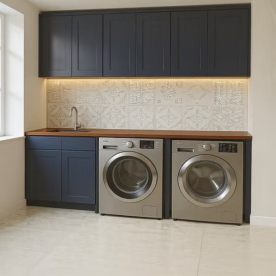 Modern laundry room with dark cabinets, wood countertop, patterned backsplash, and two front-load washer/dryer units.