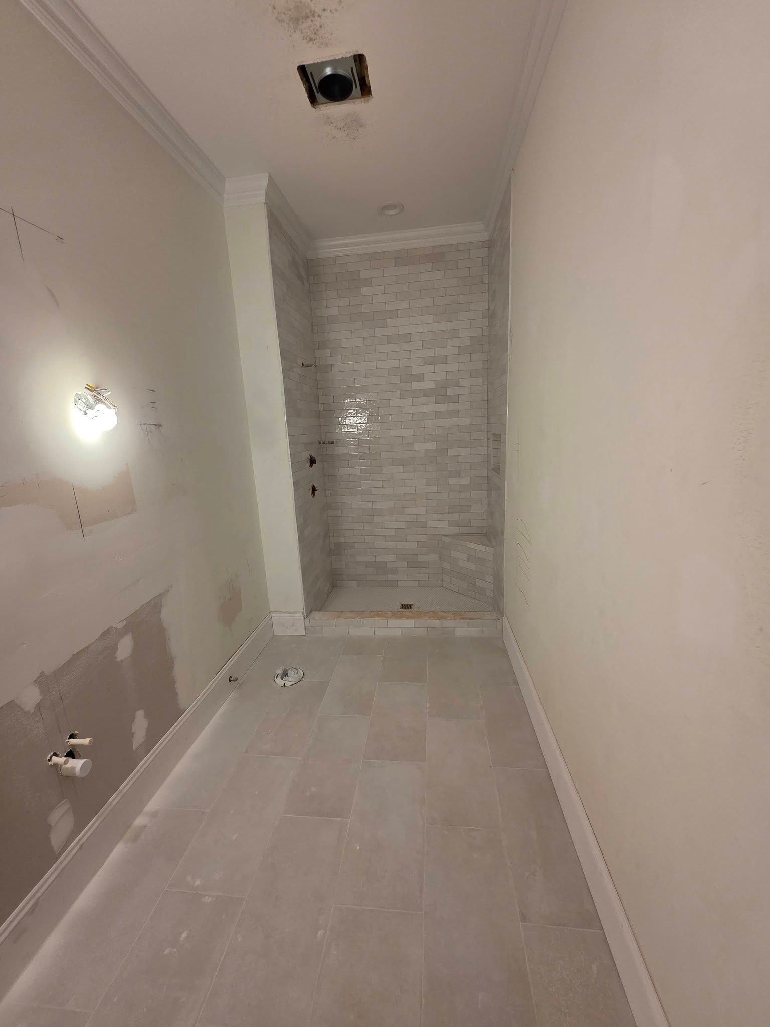 Narrow unfinished hallway with tiled floor, white walls, and exposed ceiling opening.