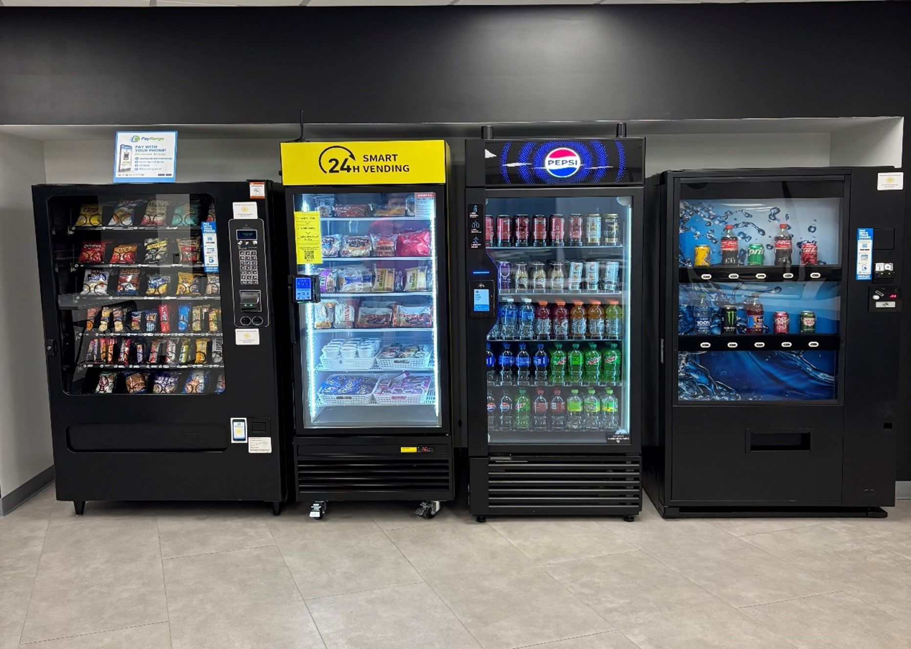 Four vending machines of snacks and beverages in a room.