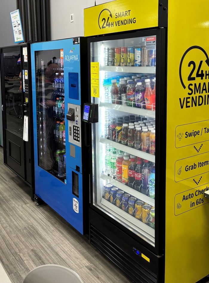Three vending machines: black, blue, and yellow, stocked with drinks.