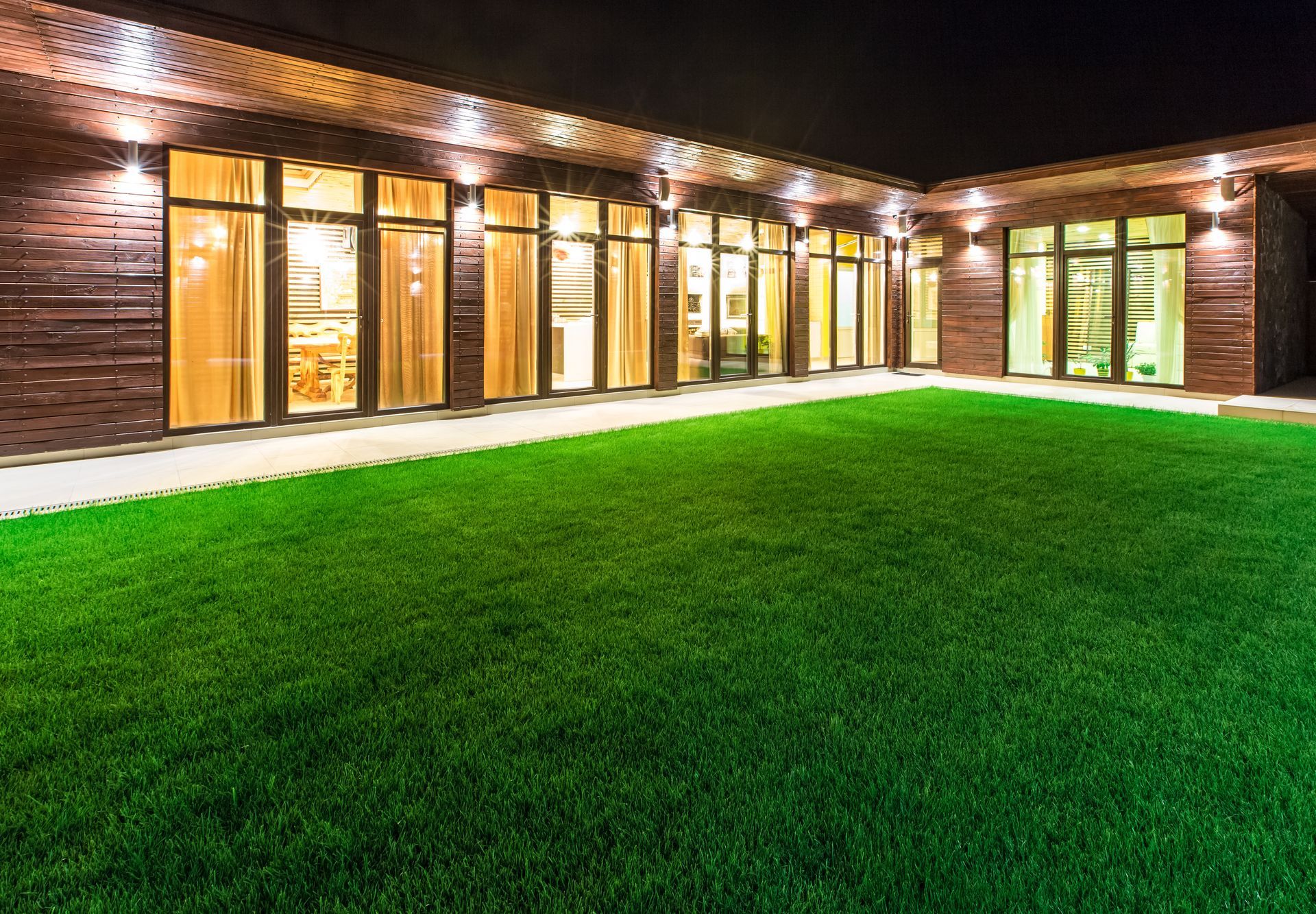 A large house with a lush green lawn in front of it at night.